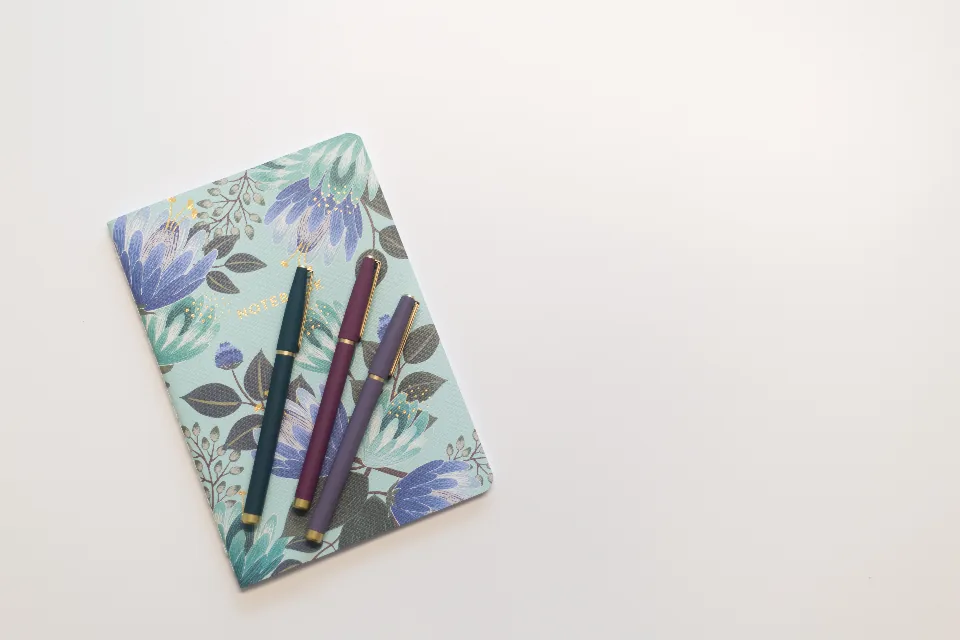 A notebook and pens on a desk, representing organization and focus tools used in adult ADHD management