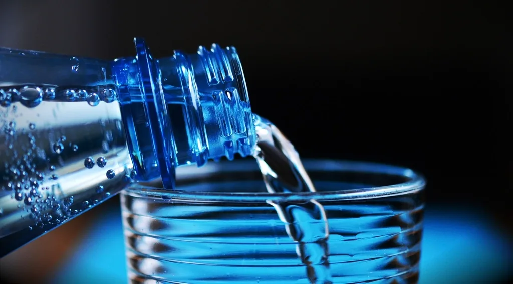 Water being poured into a glass, a reminder to stay hydrated with a urinary tract infection