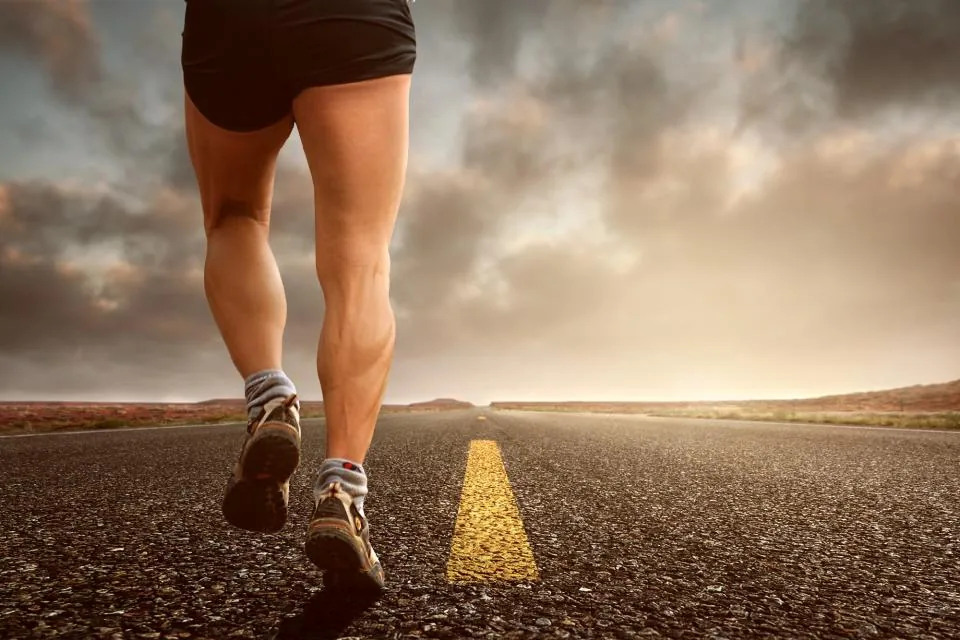 Close view of a person's legs and calves while walking on a road