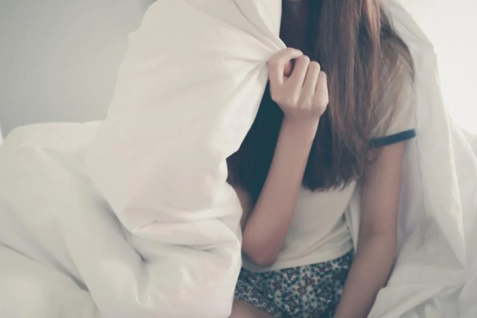 Person resting wrapped in a blanket while recovering from bronchitis at home