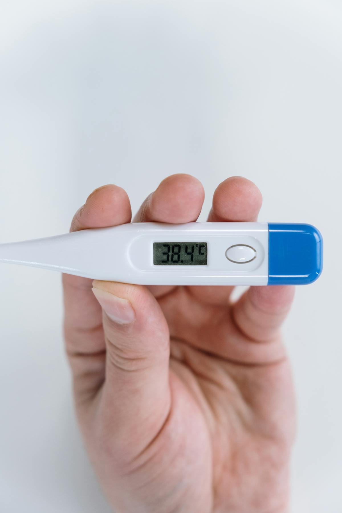Digital thermometer showing fever reading of 38.4 degrees