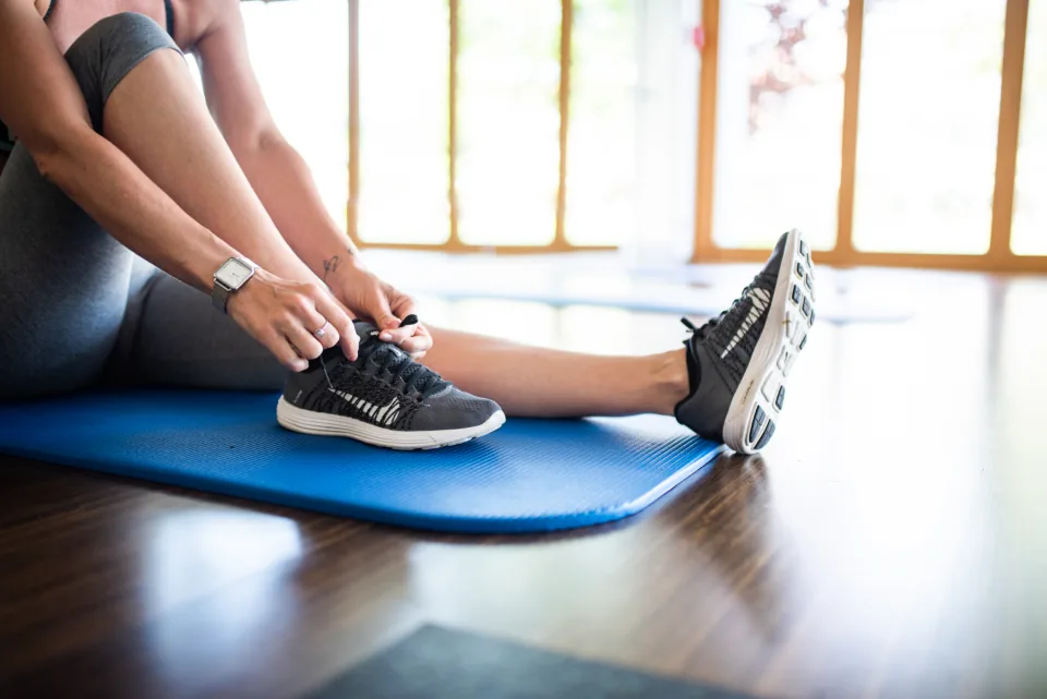 Person in athletic wear lacing shoes — staying active while managing excessive sweating