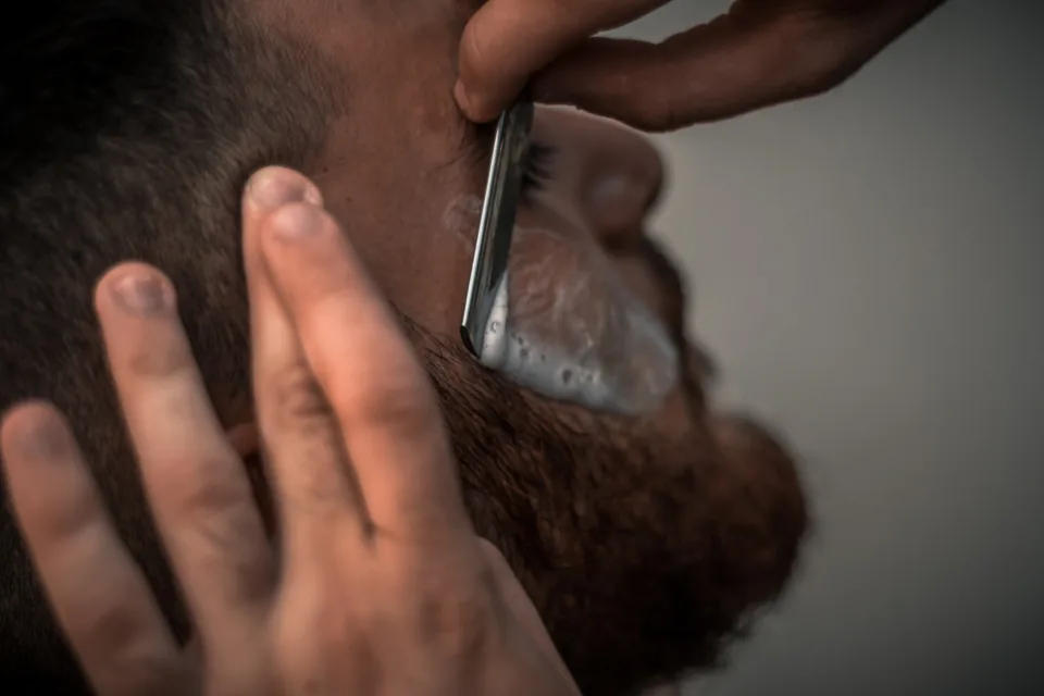 Man being shaved with a straight razor, illustrating razor-related folliculitis
