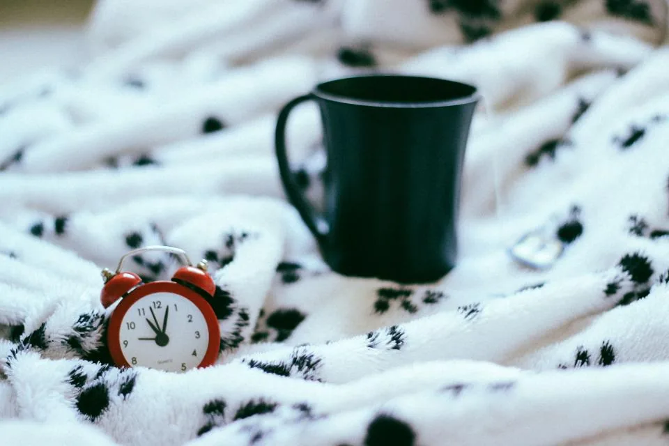 Alarm clock on a bed, representing waking at night from frequent urination
