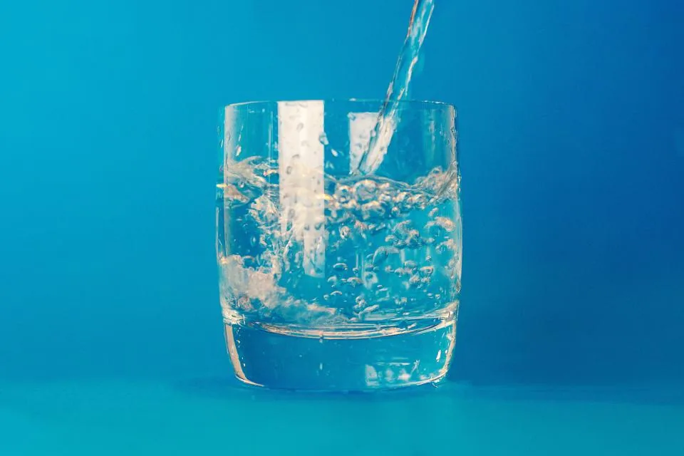 Pouring a fresh glass of water — hydration helps relieve constipation