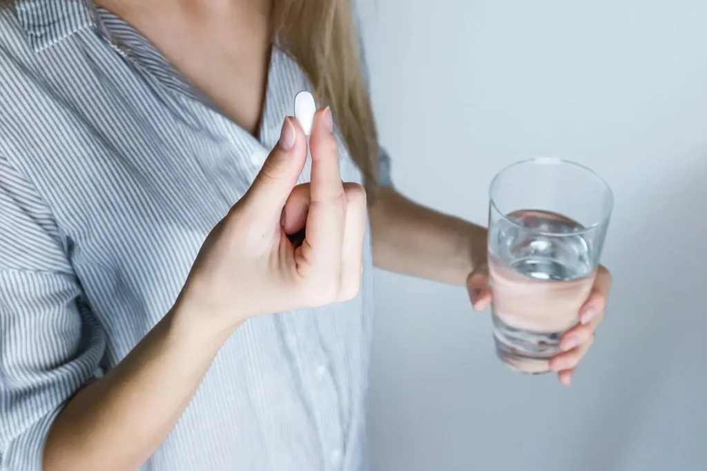 Taking medication with a glass of water for headache relief