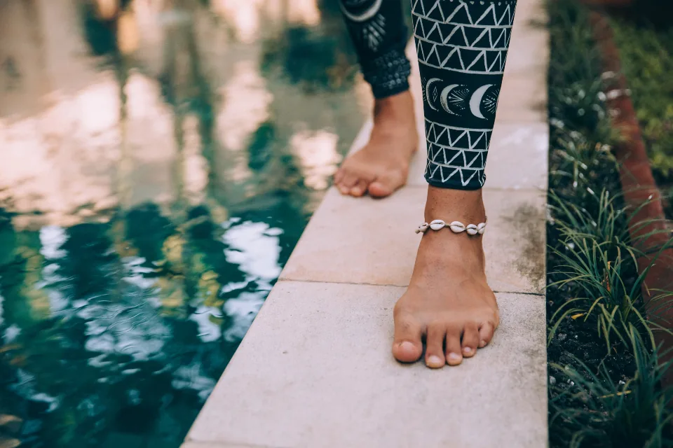 Close-up of bare feet and ankle next to water