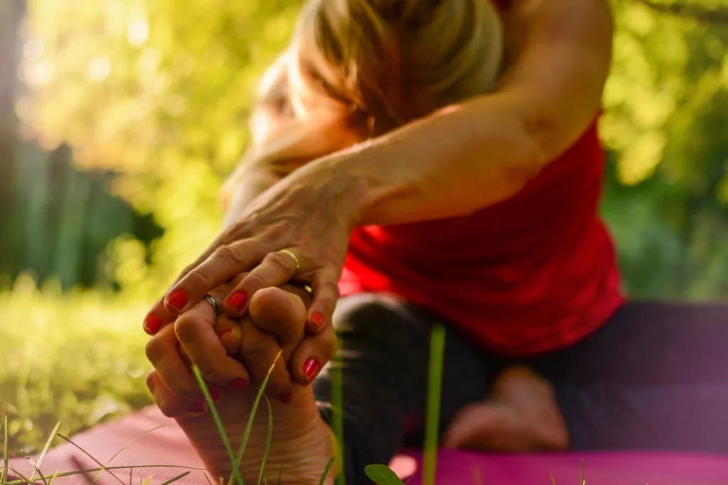 Person stretching outdoors, holding the foot to support joint mobility