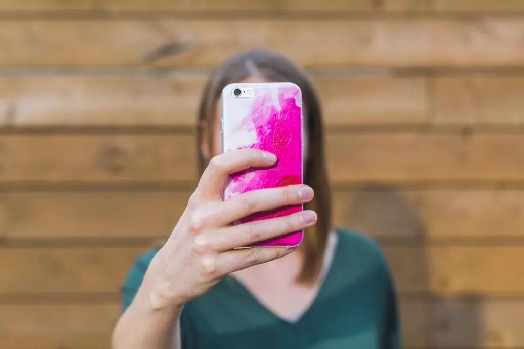 A person holding up a smartphone to take a photo, as you would to share a rash with an online doctor