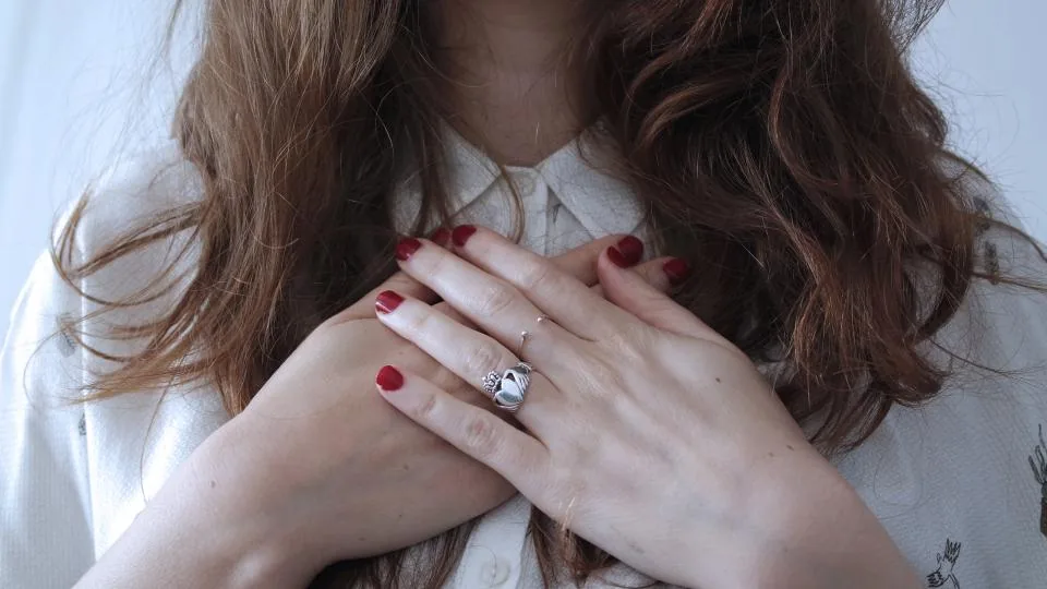 A person pressing both hands to their chest, feeling chest tightness