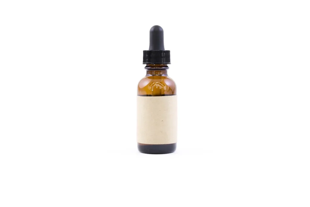An amber glass dropper bottle of eye drops on a white background