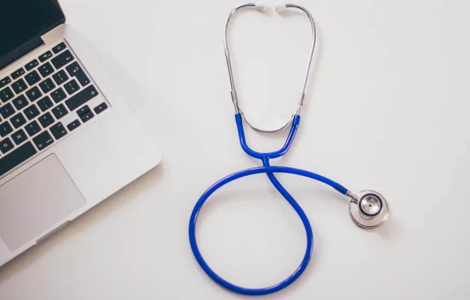 A stethoscope beside a laptop, representing a telehealth evaluation for prostatitis