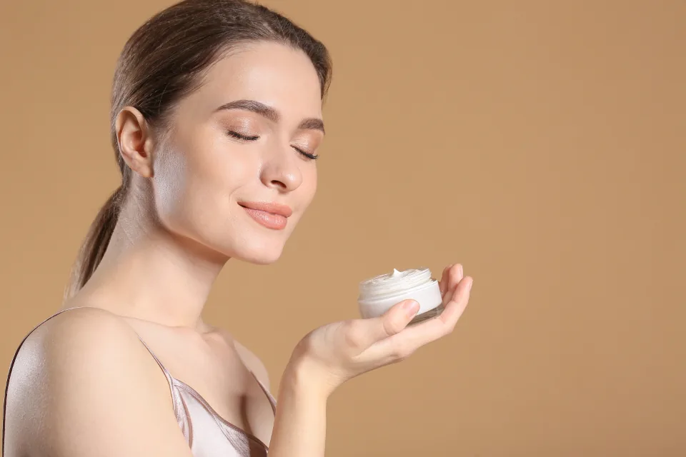A person holding a jar of topical cream used to treat skin rashes