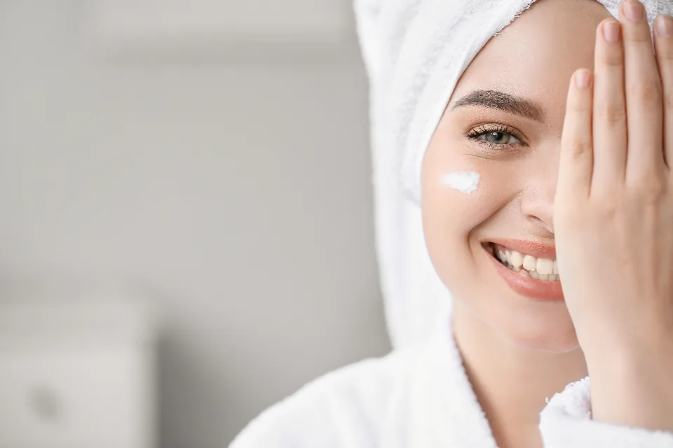 A woman applying facial cream as part of a gentle skincare routine for rosacea
