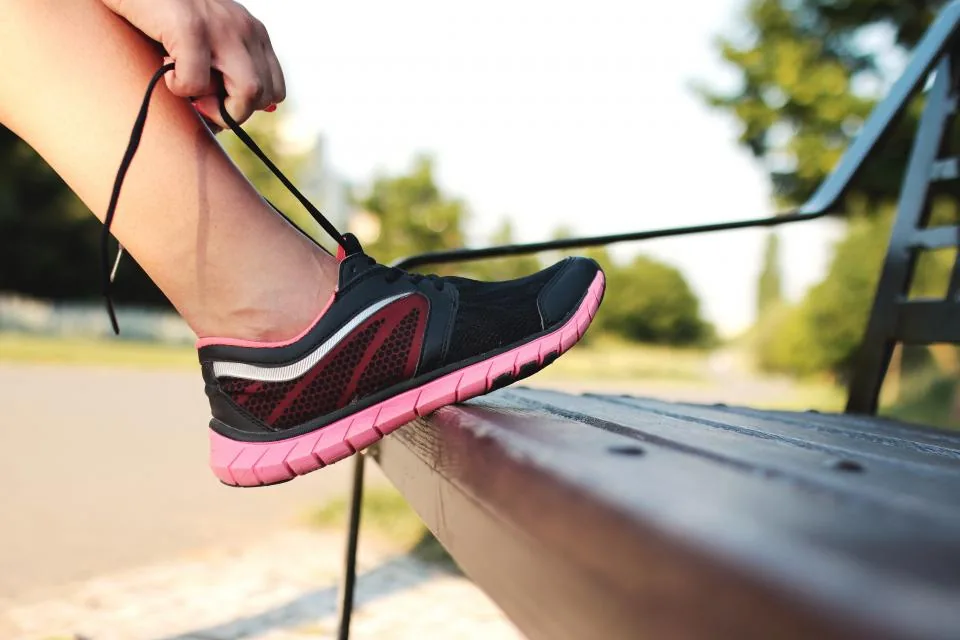 Lacing a running shoe outdoors — supportive footwear helps relieve plantar fasciitis