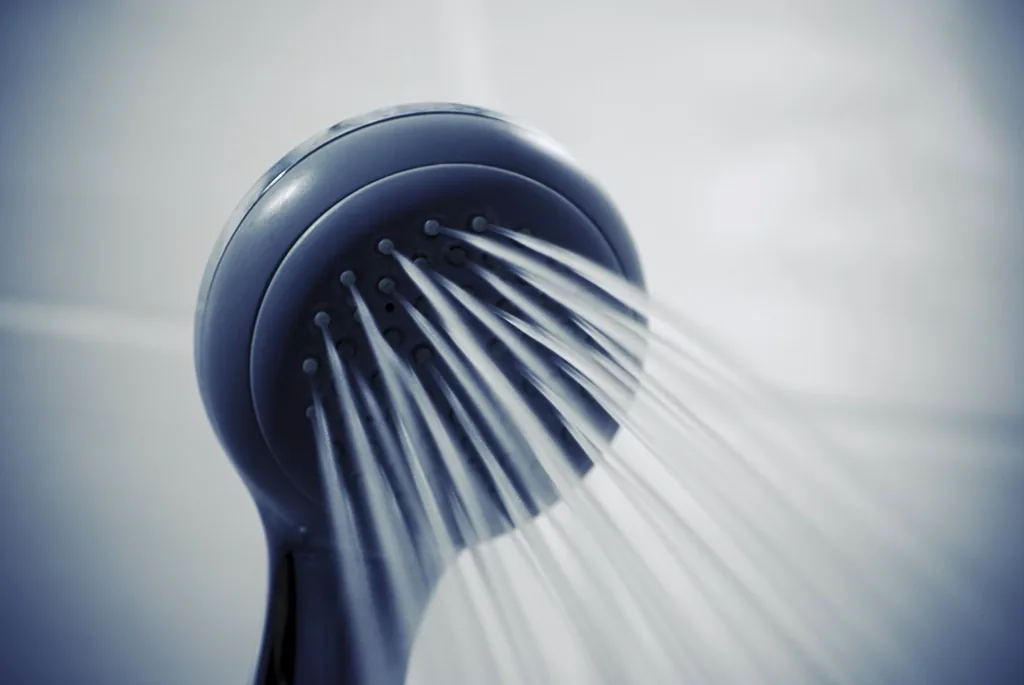 A shower head with running water, evoking the medicated shampoo and regular washing routine that controls seborrheic dermatitis