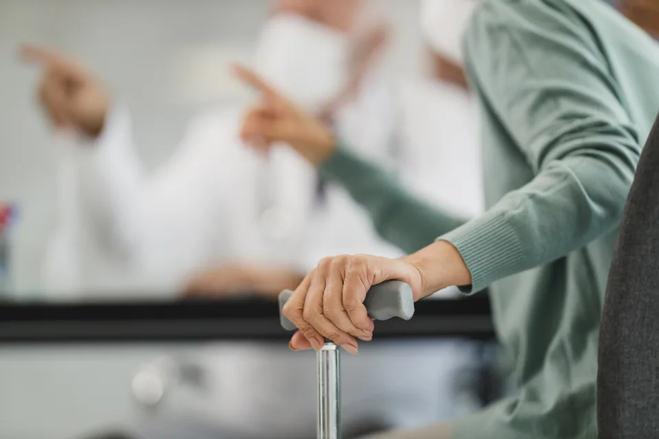 Older adult with a walking cane at a medical visit, the age group most affected by shingles