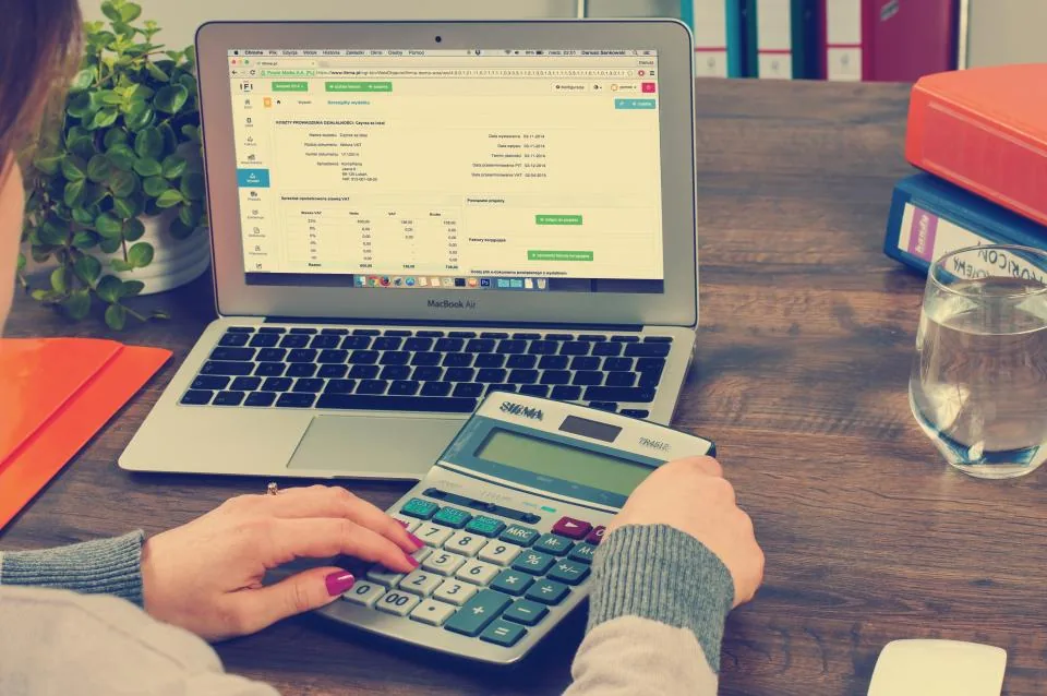 Person using a calculator and laptop to work out telehealth visit costs