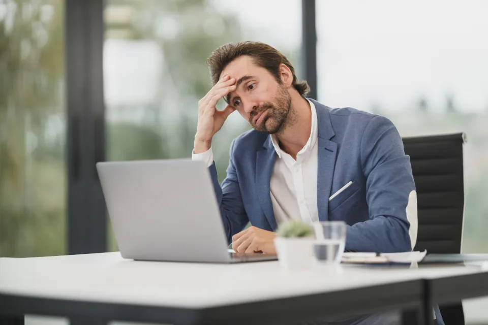 Man at a desk holding his head with a tension headache