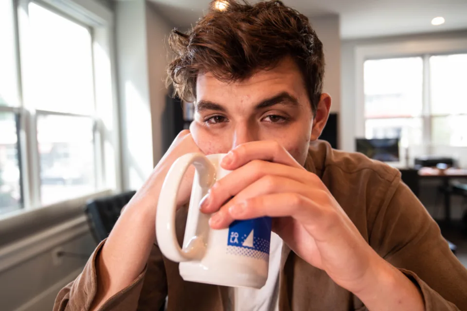 Tired young man drinking coffee to fight fatigue